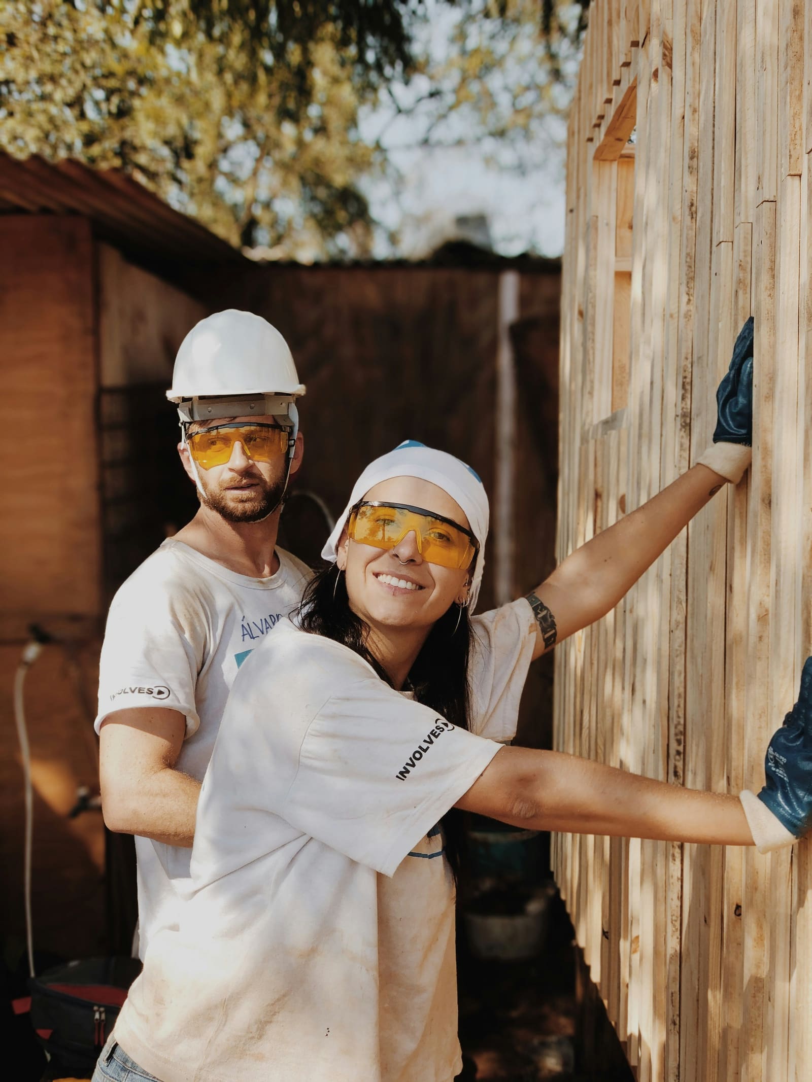 Two smiling builders working together on a wooden wall